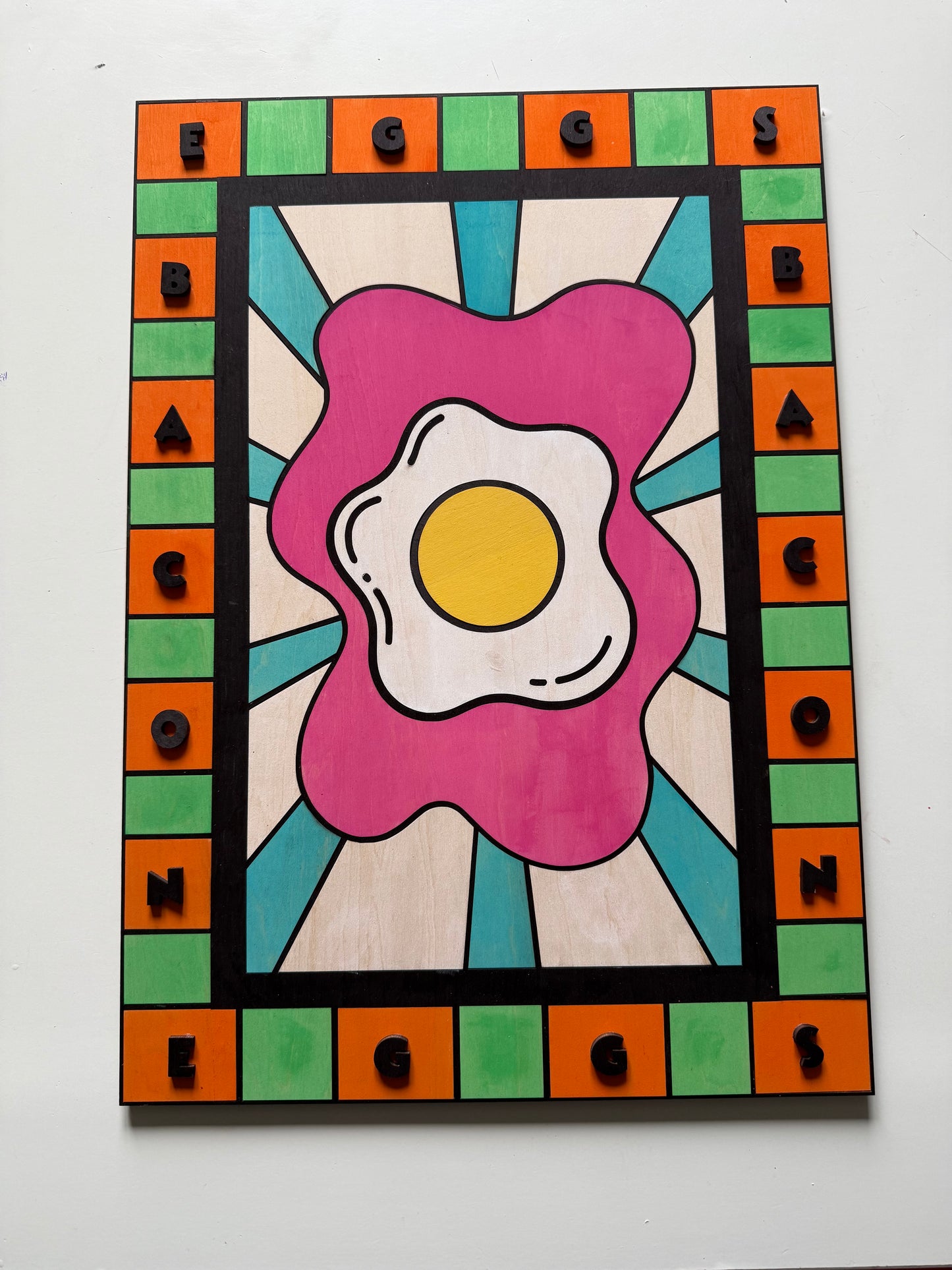 Tableau Pop Art petit-déjeuner suspendu sur un mur de cuisine en carrelage blanc, décoration artisanale en bois.