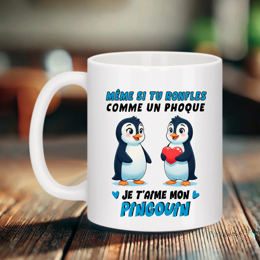 Mug blanc Bruhle avec deux pingouins mignons, l'un tenant un cœur rouge, surmontés du texte bleu et noir "Même si tu ronfles comme un phoque, je t'aime mon pingouin".