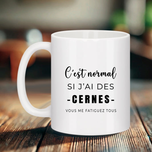 Mug blanc Bruhle avec texte noir stylisé : C'est normal si j'ai des cernes - VOUS ME FATIGUEZ TOUS.