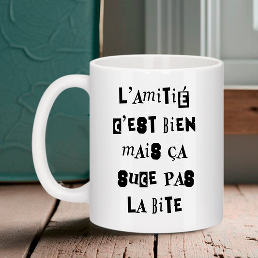 Tasse blanche Bruhle avec un texte noir déstructuré : L'AMITIÉ C'EST BIEN MAIS ÇA SUCE PAS LA BITE.