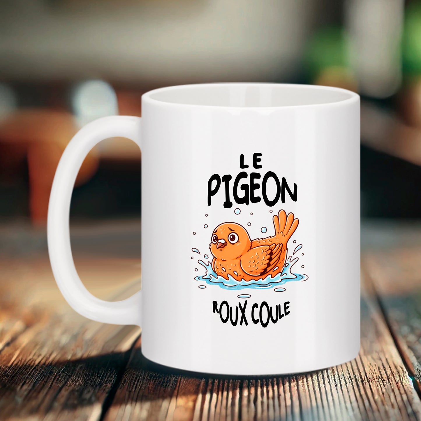 Mug blanc Bruhle sur une table en bois affichant l'illustration d'un pigeon orange souriant dans une petite flaque d'eau avec le texte "LE PIGEON" en haut et "ROUX COULE" en bas en lettres noires.