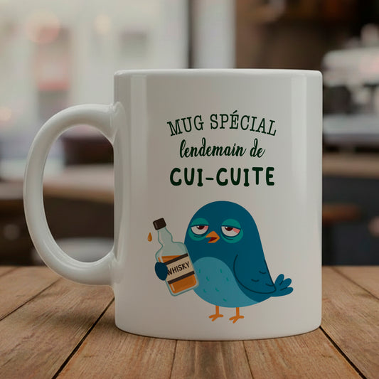 Mug en céramique blanche avec une illustration humoristique d'un petit oiseau ébouriffé, cerné et fatigué, tenant une tasse de café. Texte "Cui-cuite" écrit en gros. Design mignons mais hargneux pour lendemain de fête.