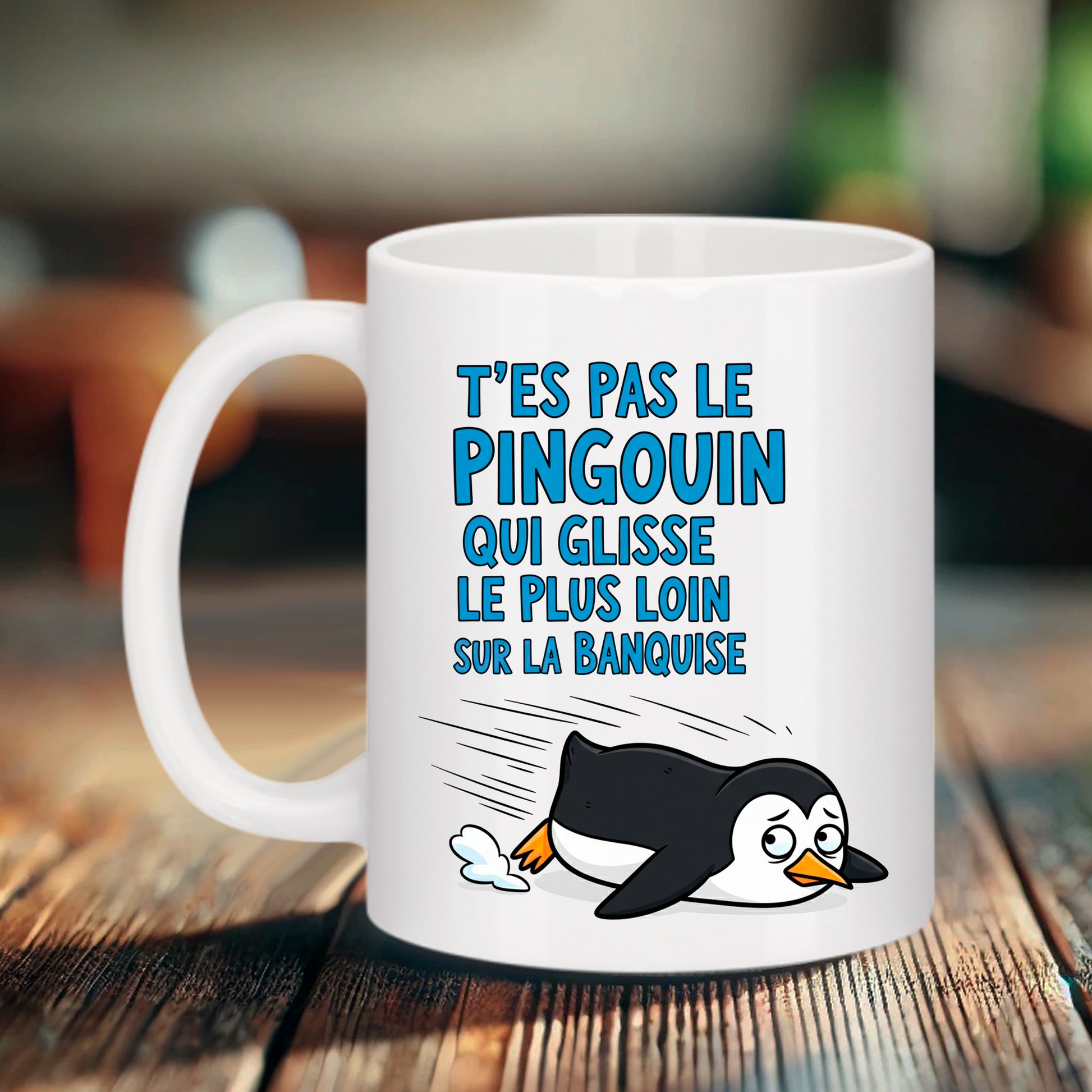 Mug blanc Bruhle avec illustration cartoon d'un pingouin glissant sur le ventre avec un air hébété et le texte bleu "T'ES PAS LE PINGOUIN QUI GLISSE LE PLUS LOIN SUR LA BANQUISE".