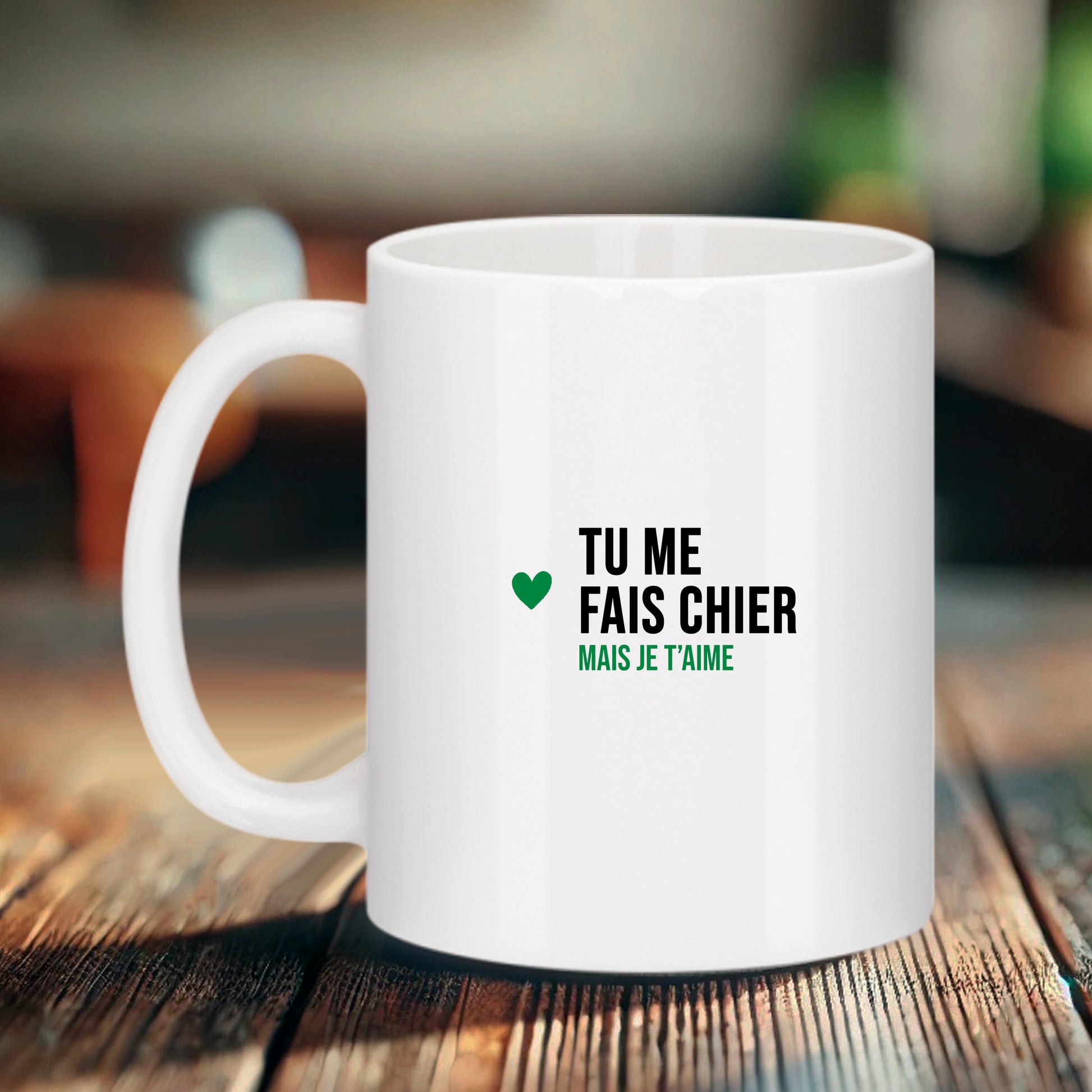 Mug blanc Bruhle avec un petit cœur vert sur la gauche et le texte noir : TU ME FAIS CHIER écrit en gras, suivi de MAIS JE T'AIME écrit en vert.