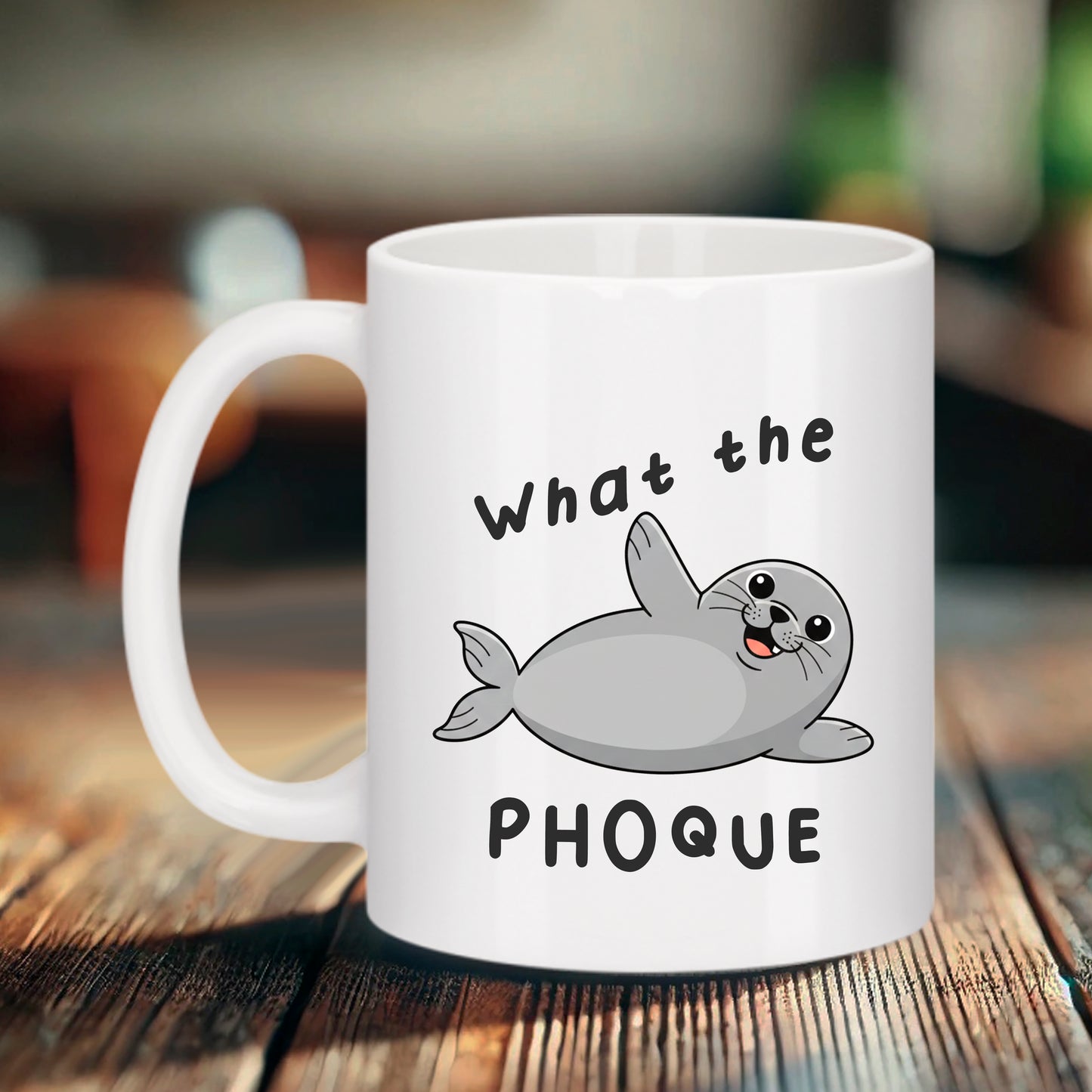 Mug blanc avec un dessin de phoque gris mignon qui fait coucou et le texte "What the PHOQUE".